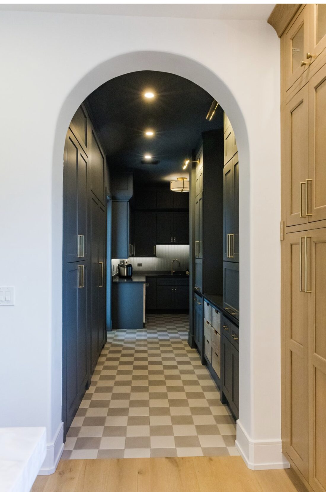Arched scullery and prep pantry with navy cabinetry and checkerboard tile floor in a South Tampa custom home by Ejt Legacy Homes